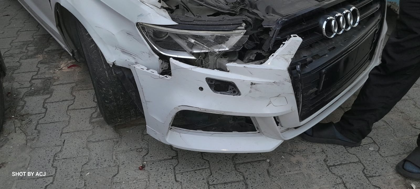 White Audi front-right headlight and bumper damage before repair